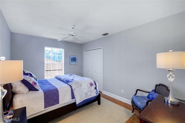 bedroom featuring visible vents, ceiling fan, baseboards, wood finished floors, and a closet