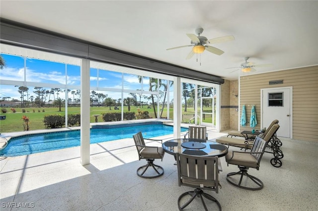 outdoor pool featuring glass enclosure, a patio, a yard, and a ceiling fan