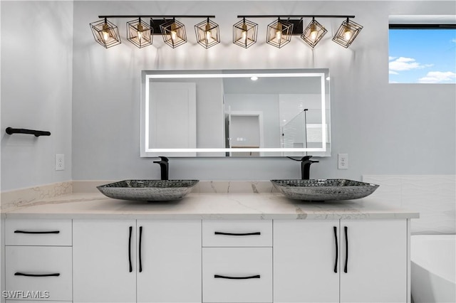 bathroom with double vanity, a bath, and a sink