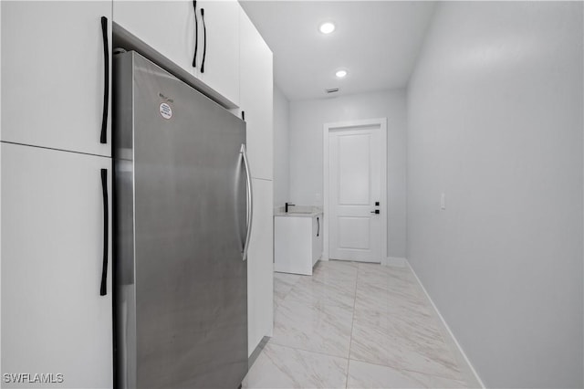 kitchen featuring baseboards, freestanding refrigerator, white cabinets, modern cabinets, and marble finish floor