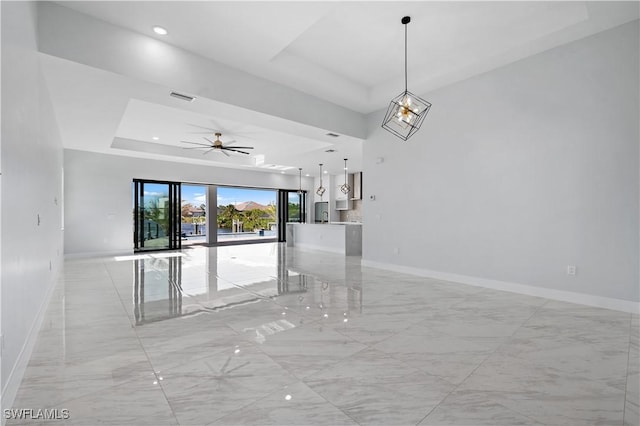 unfurnished room with a tray ceiling, baseboards, visible vents, and ceiling fan