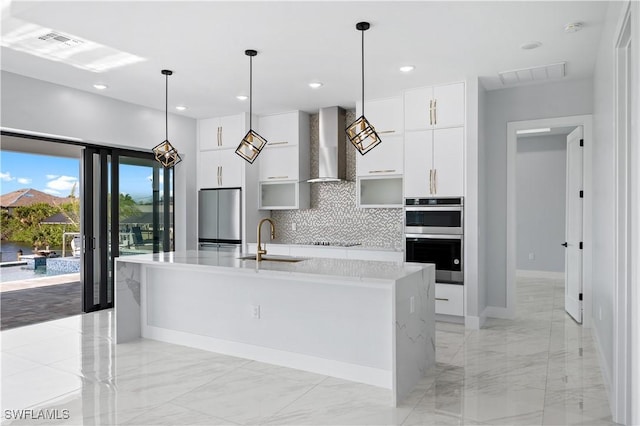 kitchen with visible vents, a sink, stainless steel appliances, wall chimney range hood, and modern cabinets