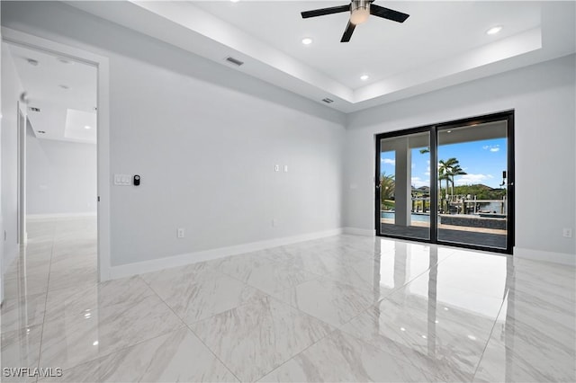 spare room with visible vents, ceiling fan, baseboards, a tray ceiling, and marble finish floor