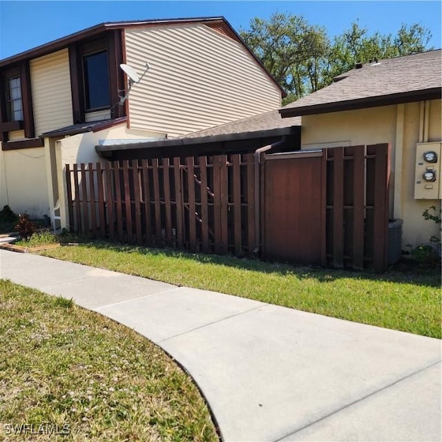 view of home's exterior featuring fence, a lawn, and stucco siding