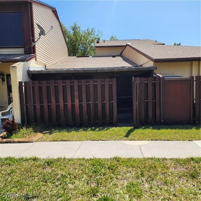 view of side of home featuring fence and a shingled roof