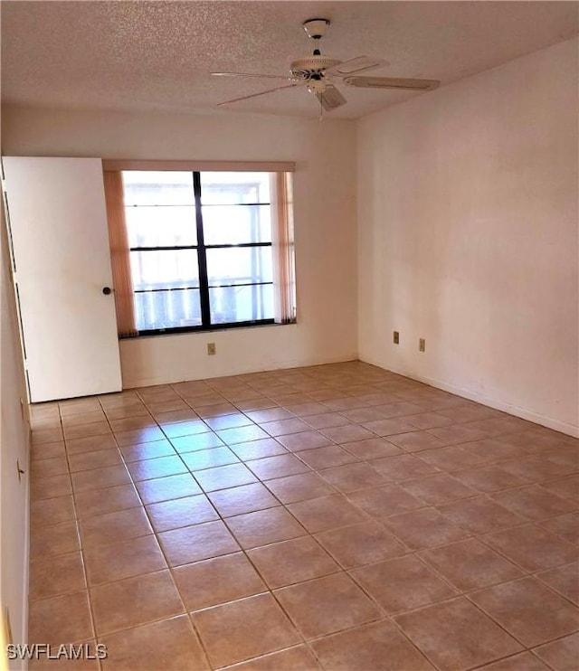 tiled empty room with a textured ceiling and a ceiling fan