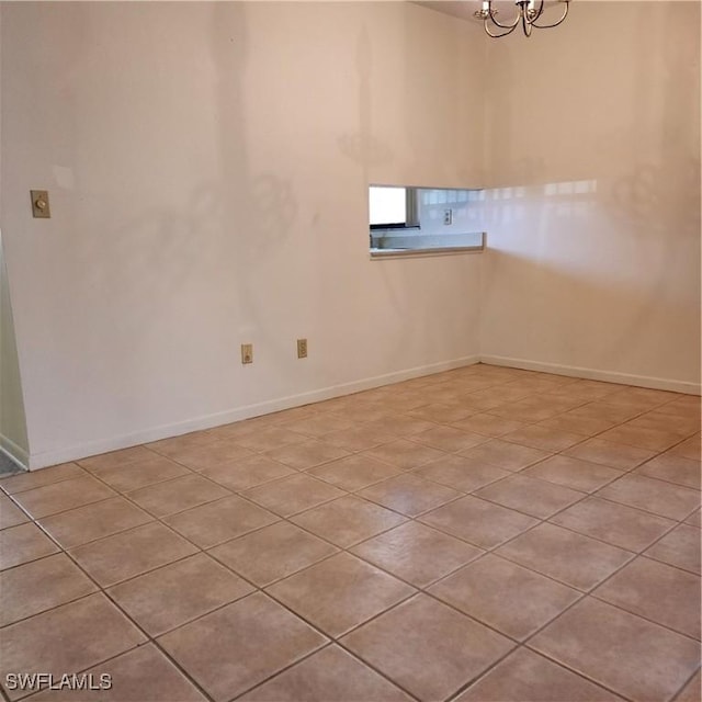 unfurnished room with baseboards and a chandelier