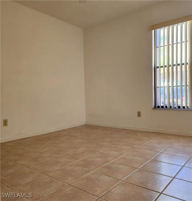 spare room with light tile patterned floors and baseboards