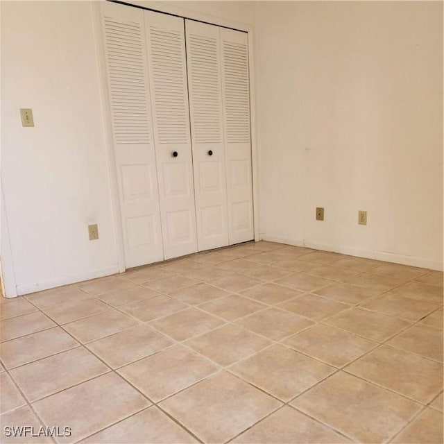 unfurnished bedroom with light tile patterned floors, baseboards, and a closet