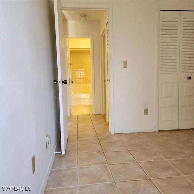 corridor with light tile patterned floors and baseboards