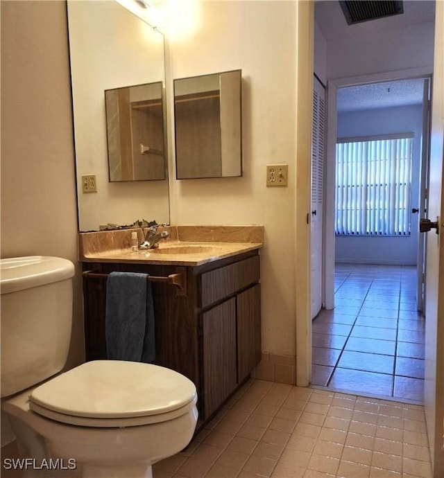 half bath featuring tile patterned floors, visible vents, toilet, and vanity