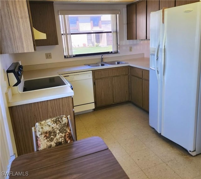 kitchen with a sink, white appliances, light floors, and light countertops