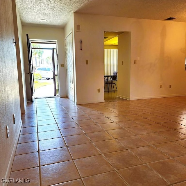 interior space with visible vents, baseboards, a textured ceiling, and tile patterned flooring