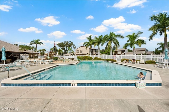 community pool with a patio area and fence