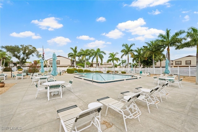 community pool with a patio and fence