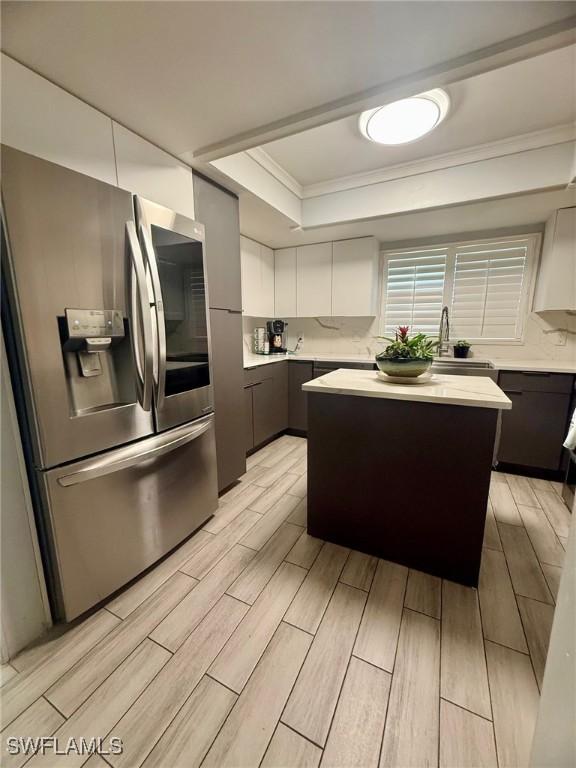 kitchen with light countertops, stainless steel fridge, a tray ceiling, and wood finish floors