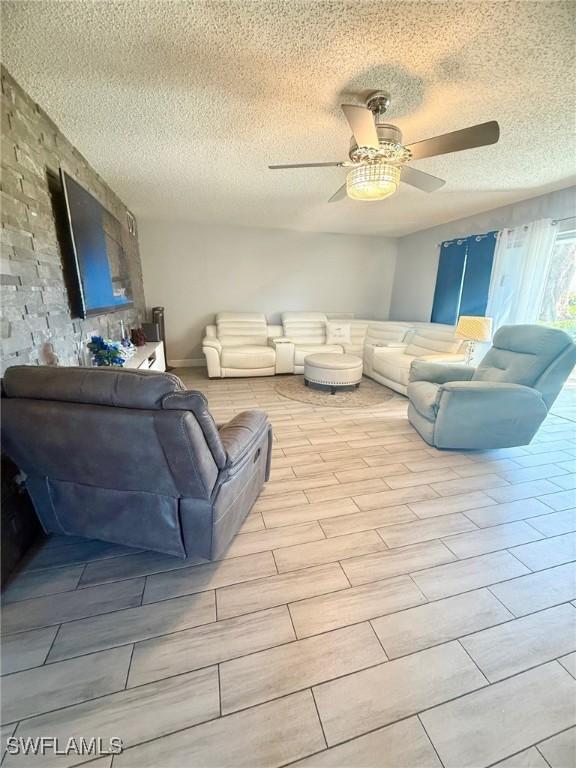 living room featuring a textured ceiling, ceiling fan, and wood tiled floor