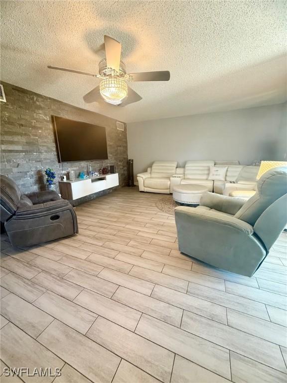 living area with a textured ceiling, wood finish floors, and ceiling fan