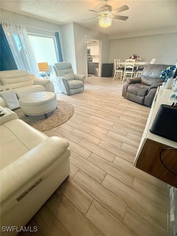 living room featuring ceiling fan, wood tiled floor, and a textured ceiling