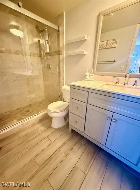 bathroom with a stall shower, toilet, vanity, and wood tiled floor