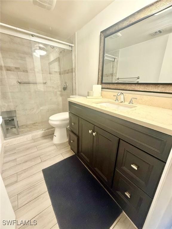 full bathroom featuring vanity, a shower stall, toilet, and visible vents