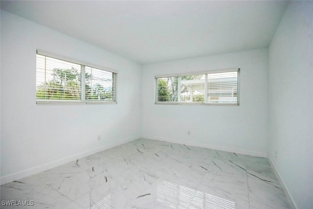 spare room with marble finish floor and baseboards