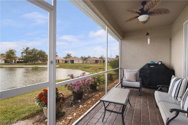 sunroom / solarium with ceiling fan and a water view