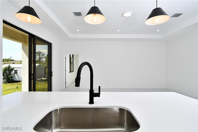 interior details with hanging light fixtures, a tray ceiling, and a sink