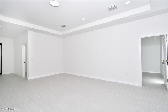 empty room featuring visible vents, recessed lighting, and a raised ceiling