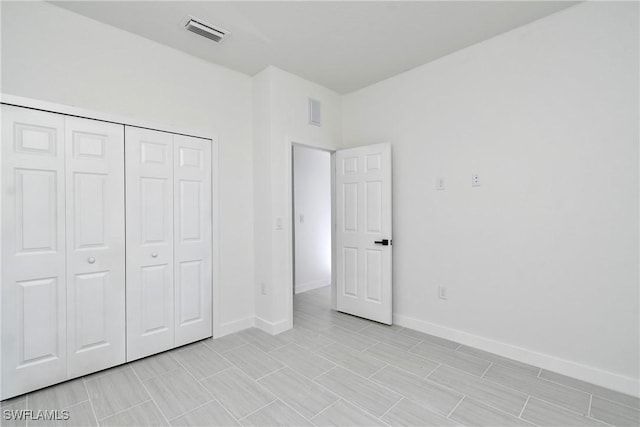 unfurnished bedroom with visible vents, baseboards, and a closet