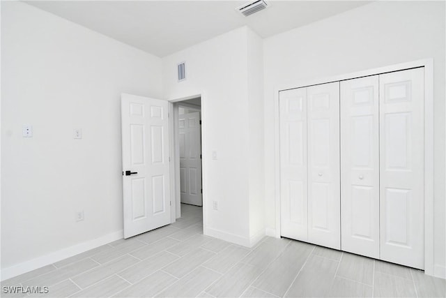 unfurnished bedroom with baseboards, visible vents, and a closet