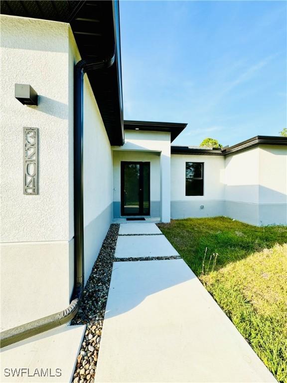 property entrance with stucco siding and a lawn