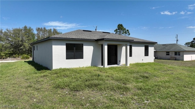3204 69th St W, Lehigh Acres, FL 33971 - rear view of house featuring stucco siding, a yard, and a shingled roof