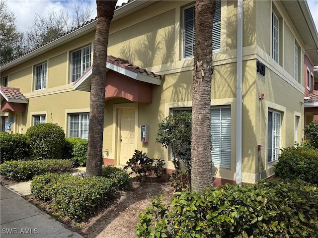 exterior space with stucco siding and a tiled roof