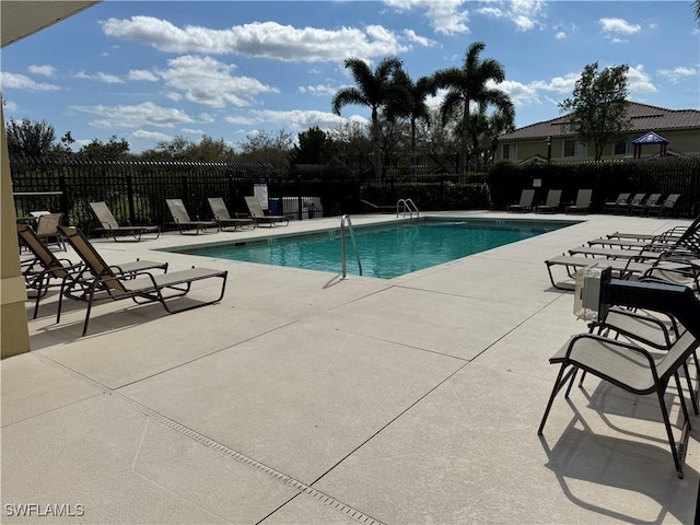 community pool with a patio and fence