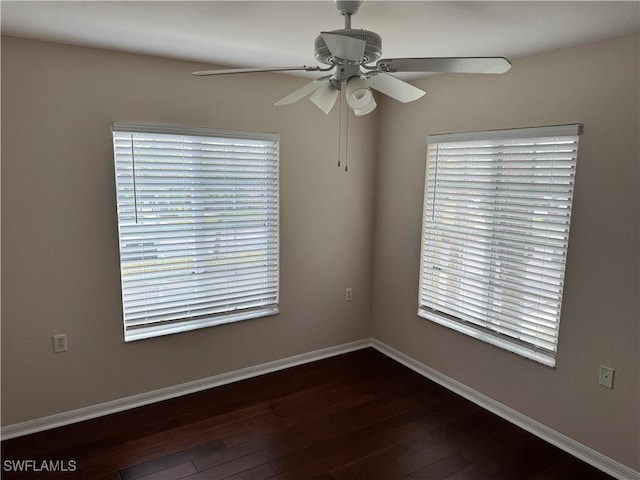 spare room with baseboards, dark wood-type flooring, a healthy amount of sunlight, and a ceiling fan