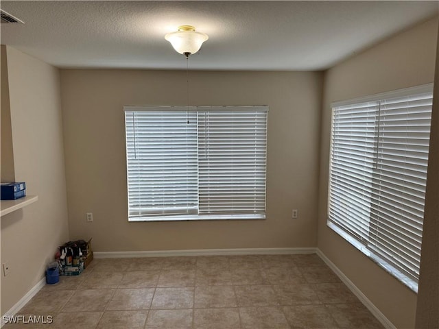 spare room with visible vents, a textured ceiling, and baseboards