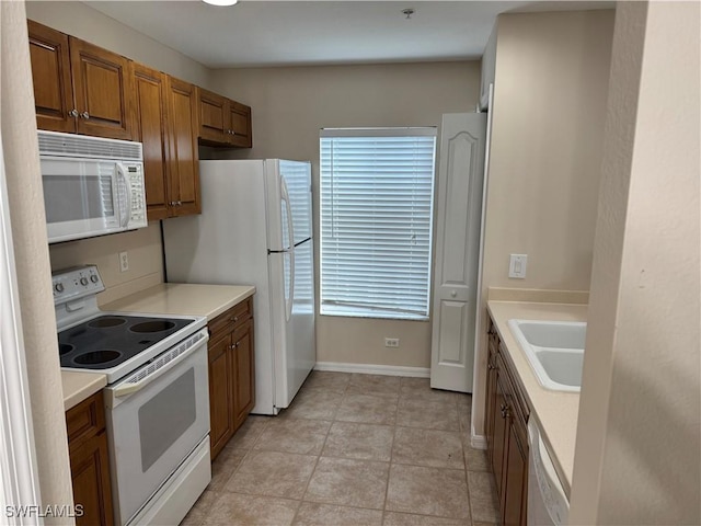 kitchen featuring white appliances, light countertops, and a sink