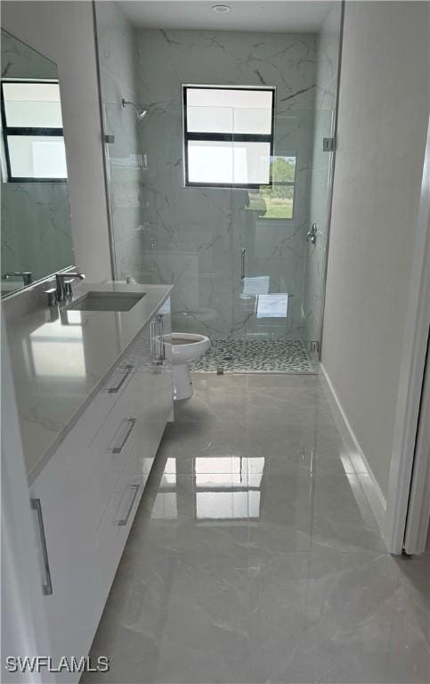 full bath with a marble finish shower, baseboards, toilet, marble finish floor, and vanity