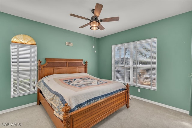 bedroom with multiple windows, light carpet, and baseboards