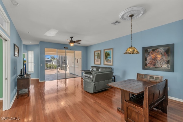 dining room featuring a ceiling fan, visible vents, wood finished floors, and baseboards