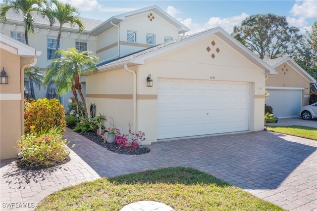 view of front of house with stucco siding, an attached garage, and decorative driveway