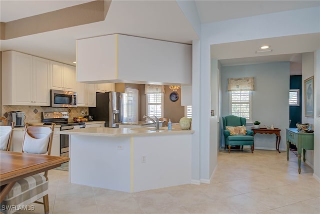 kitchen with light tile patterned flooring, a sink, light countertops, appliances with stainless steel finishes, and tasteful backsplash