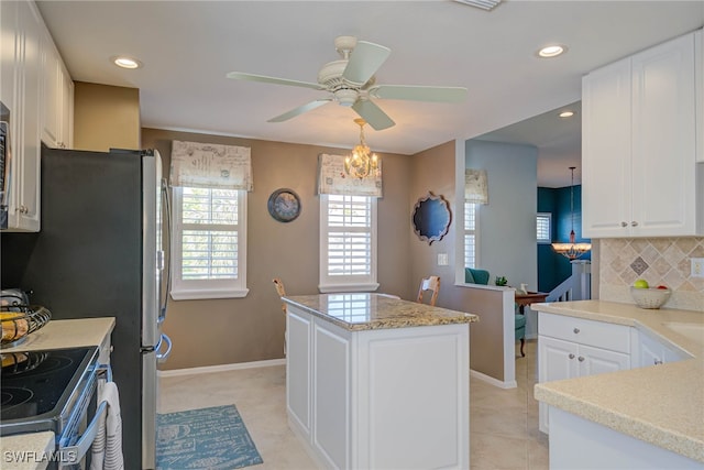 kitchen featuring a ceiling fan, a kitchen island, white cabinetry, light tile patterned floors, and decorative backsplash