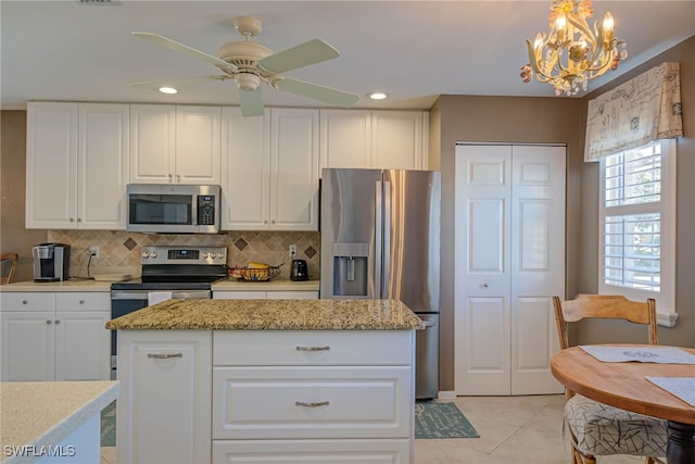 kitchen with decorative backsplash, white cabinets, ceiling fan with notable chandelier, and appliances with stainless steel finishes