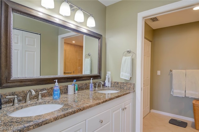 bathroom featuring a sink, visible vents, baseboards, and double vanity