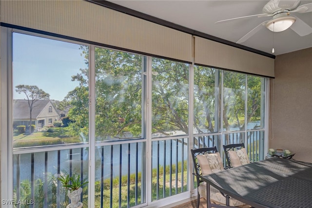 sunroom / solarium with a water view and a ceiling fan