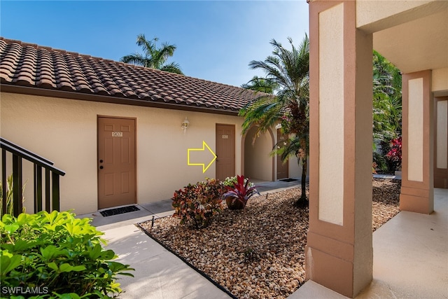 entrance to property with stucco siding and a tiled roof