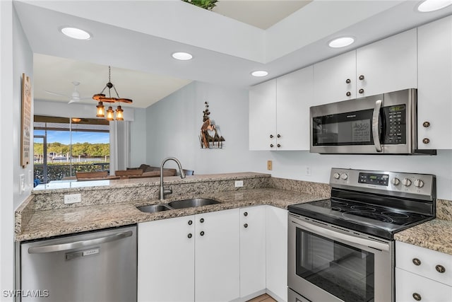 kitchen featuring a sink, white cabinetry, stainless steel appliances, a peninsula, and light stone countertops