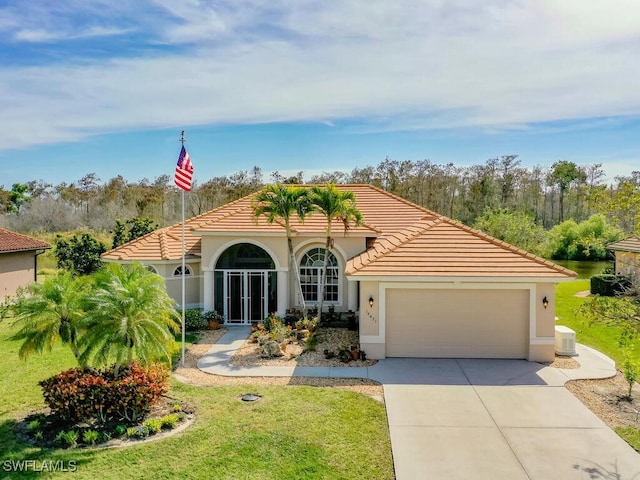 mediterranean / spanish house featuring a front lawn, a tiled roof, stucco siding, a garage, and driveway